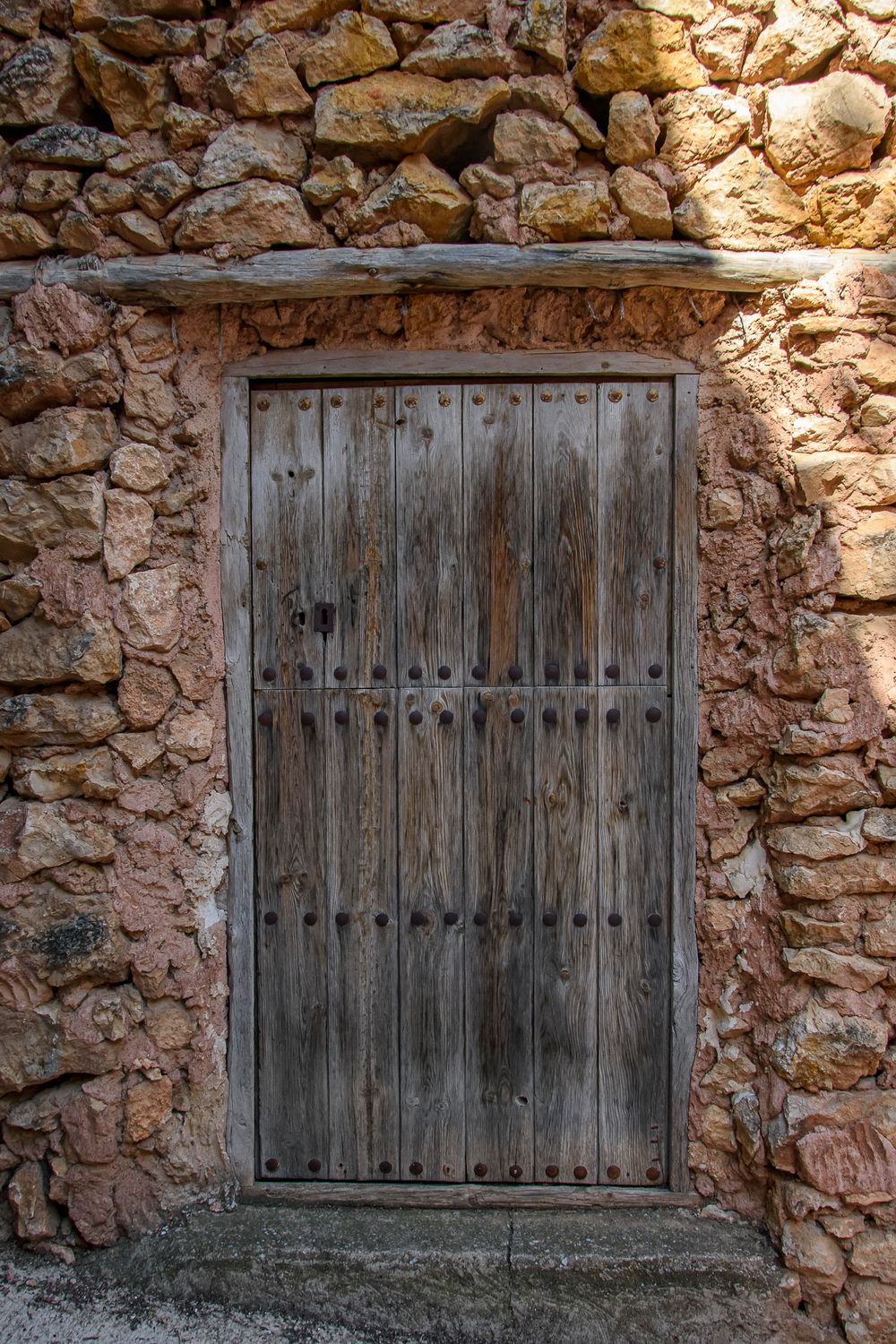 Puerta antigua de madera con clavos en un muro de mampostería